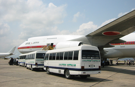 An airplane and a Logitem Vietnam shuttle bus on the airport tarmac