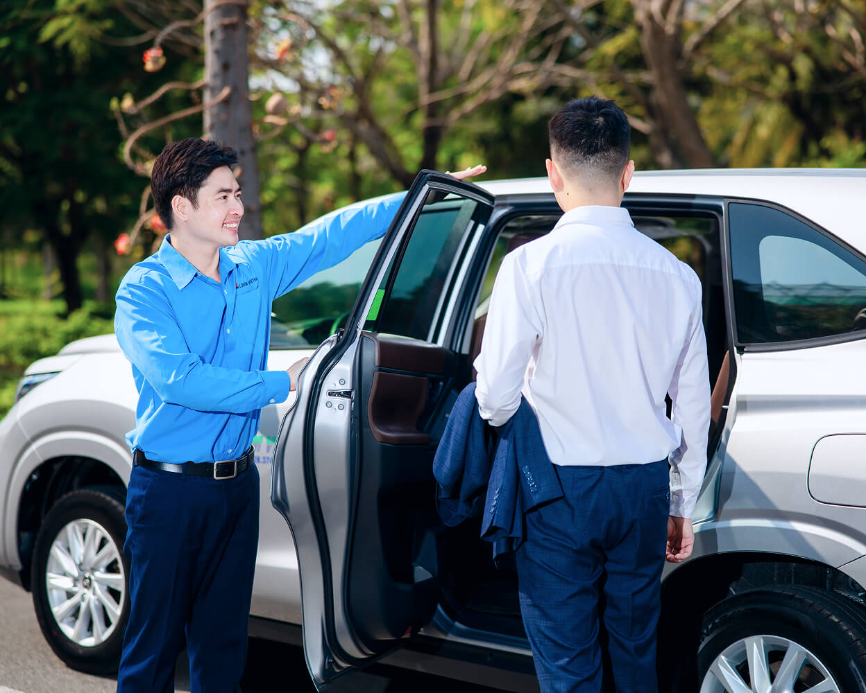 Driver greeting a businessman at a silver car