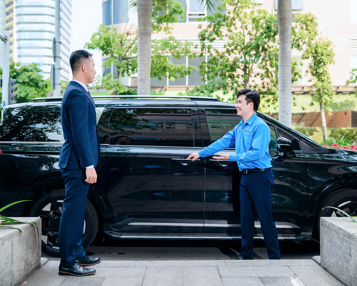 Executive and driver standing in front of a black minivan