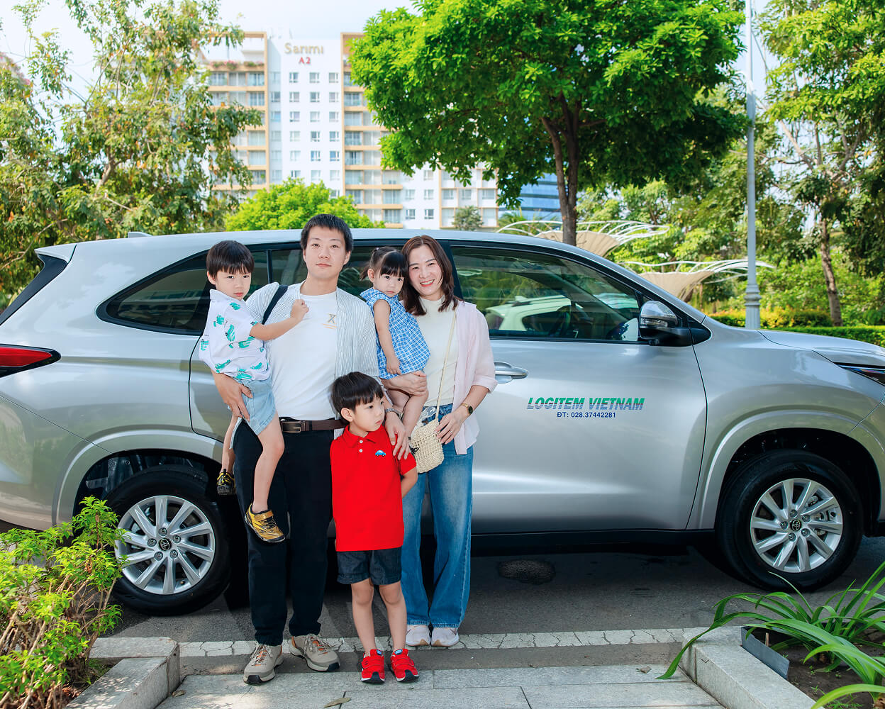 Family standing in front of a silver minivan