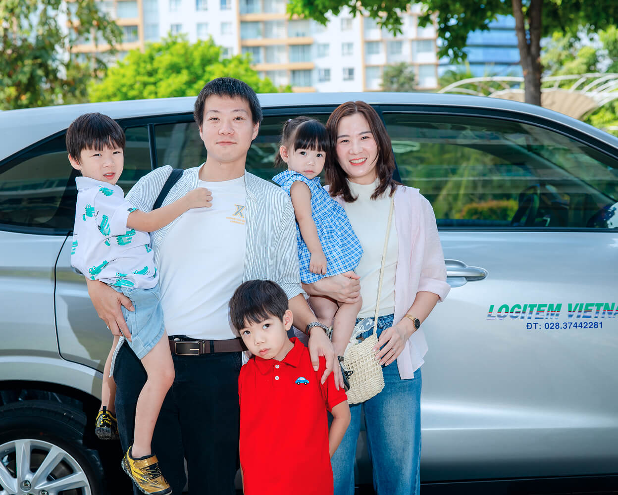 Family standing in front of a silver minivan